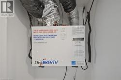Energy-efficient heat recovery ventilator unit with visible ductwork and wiring, installed within white walls - 