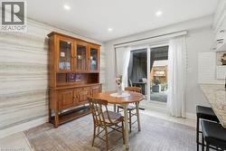 Recessed lighting illuminates the dining area featuring a sliding glass door, a wall with horizontal striped detailing, and light-toned flooring - 