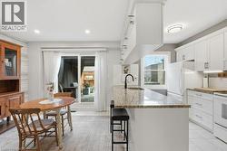 Open concept kitchen and dining area featuring white cabinetry, a granite-finish island with seating, and a white subway tile backsplash - 