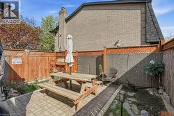 Private patio space featuring paver stone flooring, wood fencing with lattice accents, and a brick exterior wall - 