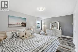 Spacious bedroom featuring wood-finish flooring, a large window, a ceiling-mounted light fixture, and a built-in closet with a white paneled door - 