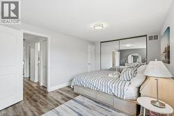 Bedroom featuring wood-finish flooring, a contemporary flush-mount ceiling light, and mirrored closet doors - 