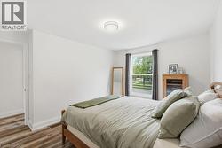 Bright interior space featuring a window with street-facing orientation, wood-finish flooring, white baseboards, and a flush-mount ceiling light fixture - 