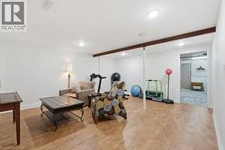 Spacious recreational area featuring recessed lighting, light wood-finish flooring, white walls, and exposed ceiling beams - 