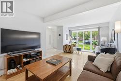 Spacious living area featuring light-toned wood-finish flooring, a contemporary accent wall, and a large window with exterior views - 