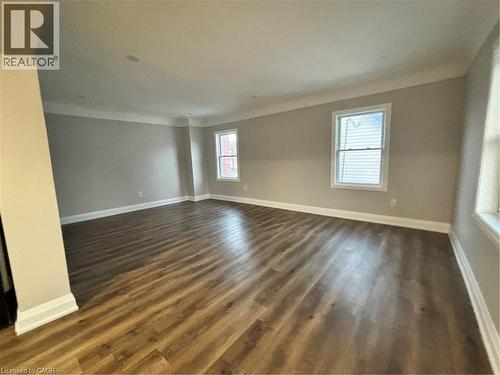 Spacious room featuring wood-finish flooring, light grey painted walls, white crown molding, and white baseboards - 773 Lawrence Road, Hamilton, ON - Indoor Photo Showing Other Room