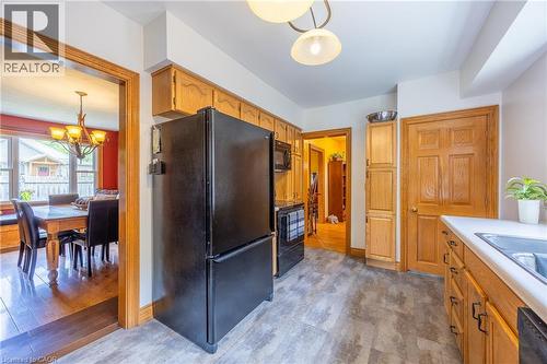 Kitchen with wood-finish cabinetry, black appliances, and durable gray flooring - 5 Hawthorne Avenue, Simcoe, ON - Indoor
