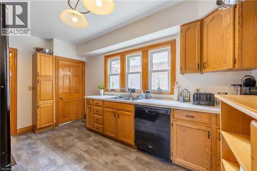 Kitchen featuring wood-finish cabinetry, solid surface countertops, and a stainless steel sink with a black dishwasher - 5 Hawthorne Avenue, Simcoe, ON - Indoor Photo Showing Kitchen With Double Sink
