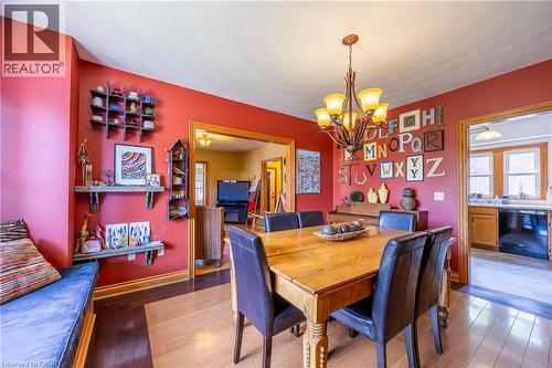 Dining area featuring red walls and a multi-tone wood-finish floor - 5 Hawthorne Avenue, Simcoe, ON - Indoor Photo Showing Dining Room