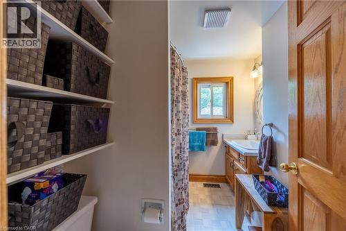 Bathroom featuring a wood-finish vanity with an integrated sink, a rectangular window with wood trim, and tile flooring - 5 Hawthorne Avenue, Simcoe, ON - Indoor
