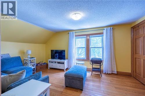Room featuring wood-finish flooring, natural wood window trim, a ceiling-mounted light fixture, and a paneled wood door - 5 Hawthorne Avenue, Simcoe, ON - Indoor Photo Showing Living Room