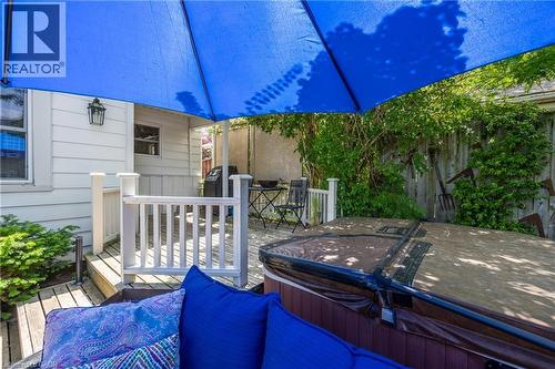 Multi-level outdoor deck featuring a hot tub, white railings, and a privacy fence with mature greenery - 5 Hawthorne Avenue, Simcoe, ON - Outdoor With Deck Patio Veranda