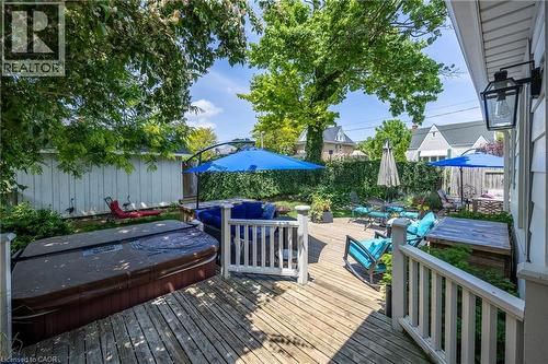Expansive wood deck featuring a covered outdoor spa, white picket railing, and mature trees providing natural canopy - 5 Hawthorne Avenue, Simcoe, ON - Outdoor With Deck Patio Veranda