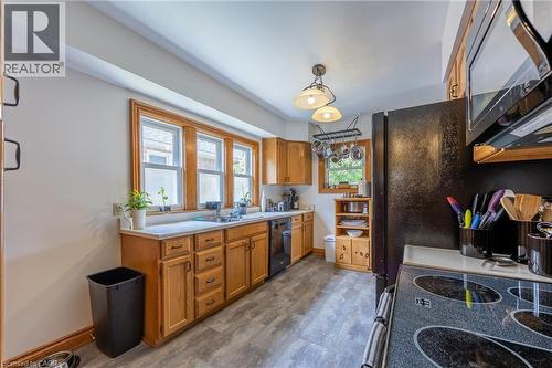 Kitchen featuring wood-finish cabinetry, light-toned countertops, and wood-trim windows - 5 Hawthorne Avenue, Simcoe, ON - Indoor Photo Showing Kitchen With Double Sink
