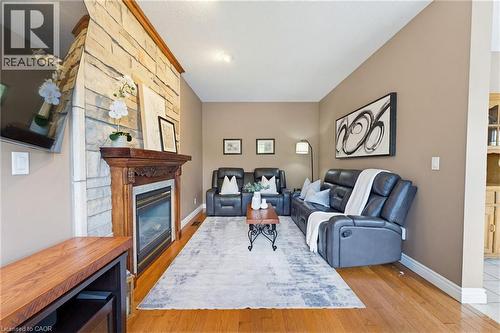 Living area showcasing a stone-clad fireplace with a carved wood mantle, hardwood flooring, and neutral wall tones - 29 Watson Crescent, Ayr, ON - Indoor Photo Showing Living Room With Fireplace