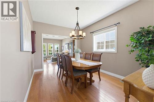 Dining area featuring wood-finish flooring, a contemporary chandelier, and a large window with blinds - 29 Watson Crescent, Ayr, ON - Indoor Photo Showing Dining Room