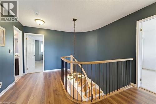 Curved staircase with wood-finish handrail and black metal balusters - 29 Watson Crescent, Ayr, ON - Indoor Photo Showing Other Room