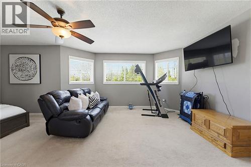 Spacious room featuring neutral carpeting, light gray walls, a ceiling fan with integrated lighting, and three large windows with horizontal blinds - 29 Watson Crescent, Ayr, ON - Indoor Photo Showing Gym Room