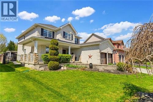 Two-story brick residence featuring a covered front porch with stone columns and white railing - 29 Watson Crescent, Ayr, ON - Outdoor
