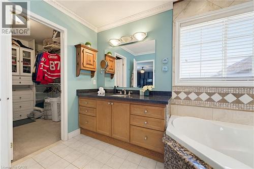 Bathroom featuring a built-in corner tub with a granite surround, a single vanity with wood cabinetry and a dark countertop, and a window with horizontal blinds - 29 Watson Crescent, Ayr, ON - Indoor Photo Showing Bathroom