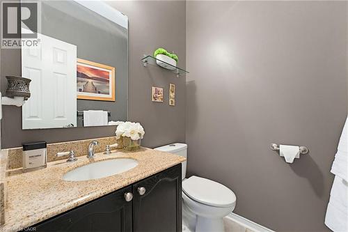 Bathroom vanity featuring a light speckled countertop, undermount sink, and dark wood-finish cabinetry - 29 Watson Crescent, Ayr, ON - Indoor Photo Showing Bathroom