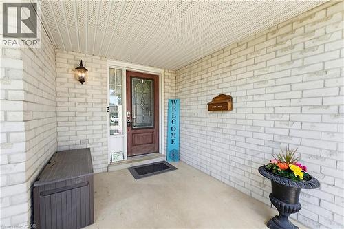 Covered porch entry featuring white brick siding and a decorative front door with leaded glass accents - 29 Watson Crescent, Ayr, ON - Outdoor With Exterior