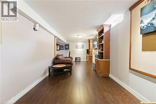 Spacious lower level featuring wood-finish flooring, recessed lighting, and built-in oak cabinetry with shelving - 29 Watson Crescent, Ayr, ON - Indoor Photo Showing Other Room