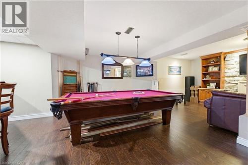 Recreation room featuring wood-finish flooring, a pool table with pendant lighting, a built-in wood bookcase, and a stone accent wall - 29 Watson Crescent, Ayr, ON - Indoor Photo Showing Other Room