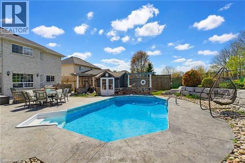 Backyard oasis with a geometric inground pool, stamped concrete patio, and a dedicated pool house - 29 Watson Crescent, Ayr, ON - Outdoor With In Ground Pool