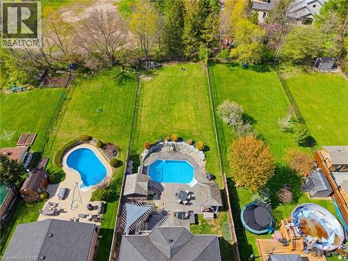 Expansive property featuring a large backyard with two distinct pools, extensive paved patio space, mature trees, and a manicured lawn - 29 Watson Crescent, Ayr, ON - Outdoor With In Ground Pool