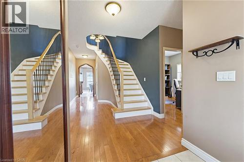 Gracious foyer featuring wood-finish flooring, a curved staircase with wrought iron balusters, and a decorative arched doorway - 29 Watson Crescent, Ayr, ON - Indoor Photo Showing Other Room