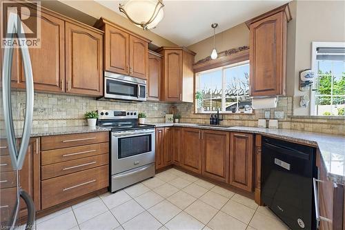 Kitchen featuring wood cabinetry, granite countertops, tile flooring, a tile backsplash, and stainless steel appliances - 29 Watson Crescent, Ayr, ON - Indoor Photo Showing Kitchen