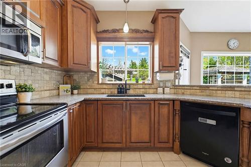 Kitchen with wood cabinetry, granite-finish countertops, and a tiled backsplash - 29 Watson Crescent, Ayr, ON - Indoor Photo Showing Kitchen