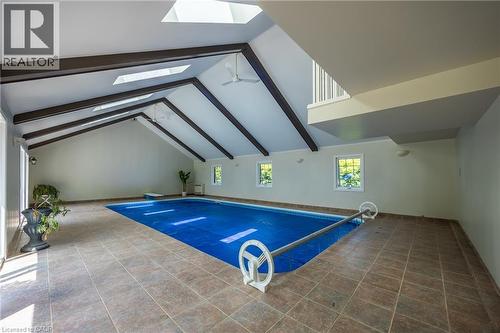 Indoor swimming pool featuring a vaulted ceiling with exposed beams, multiple skylights, and ceiling fans - 1 Bostwick Crescent, Lynedoch, ON - Indoor Photo Showing Other Room With In Ground Pool