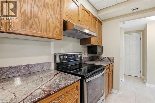 Kitchen featuring wood cabinetry, marbled countertops, and a stainless steel range with overhead ventilation - 10 Ellen Street E Unit# 808, Kitchener, ON - Indoor Photo Showing Kitchen