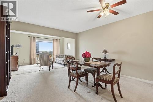 Carpeted living area featuring a built-in bookshelf, a ceiling fan with light kit, a large window opening to an outdoor area, and neutral wall tones - 10 Ellen Street E Unit# 808, Kitchener, ON - Indoor Photo Showing Dining Room