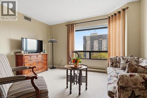 Bright living space featuring a large picture window with city views, light-toned carpeting, neutral wall paint, and perimeter heating - 10 Ellen Street E Unit# 808, Kitchener, ON - Indoor