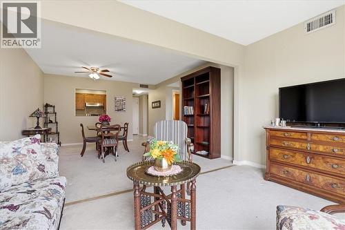 Expansive living area featuring light neutral wall tones, plush carpet flooring, a pass-through window to the kitchen, and a ceiling fan - 10 Ellen Street E Unit# 808, Kitchener, ON - Indoor Photo Showing Living Room