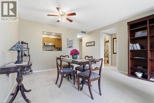 Open-concept dining area featuring light-toned carpeting, a ceiling fan, and a pass-through window to the kitchen - 10 Ellen Street E Unit# 808, Kitchener, ON - Indoor Photo Showing Dining Room