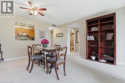 Dining area featuring a pass-through window to the kitchen, a ceiling fan, and light-colored carpeting - 10 Ellen Street E Unit# 808, Kitchener, ON - Indoor Photo Showing Dining Room