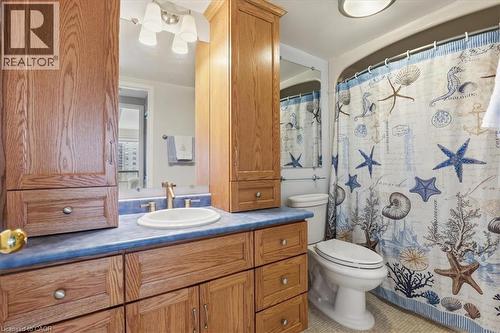 Bathroom featuring a single basin vanity with wood cabinetry, blue countertop, and a vanity mirror with overhead lighting - 10 Ellen Street E Unit# 808, Kitchener, ON - Indoor Photo Showing Bathroom