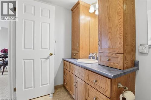 Bathroom vanity featuring wood-finish cabinetry, a white basin, gray countertop, and built-in vertical storage - 10 Ellen Street E Unit# 808, Kitchener, ON - Indoor Photo Showing Bathroom