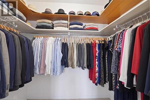 Spacious walk-in closet featuring extensive built-in shelving, multiple hanging rods, and wood-finish upper storage - 10 Ellen Street E Unit# 808, Kitchener, ON - Indoor With Storage
