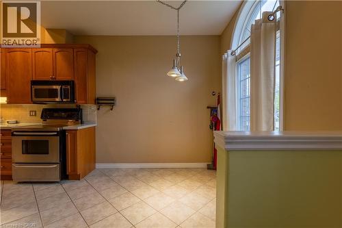 Kitchen area featuring wood cabinetry, stainless steel appliances, and tiled flooring - 4066 Medland Drive, Burlington, ON - Indoor Photo Showing Kitchen