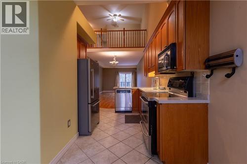 Kitchen featuring wood cabinetry, stainless steel appliances, tiled flooring, and light-toned countertops - 4066 Medland Drive, Burlington, ON - Indoor Photo Showing Kitchen