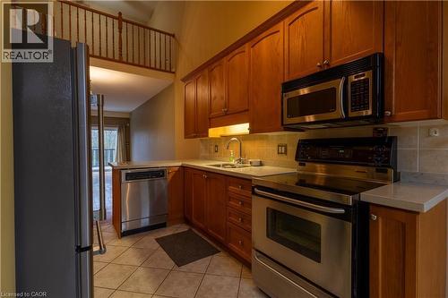 Kitchen featuring tile flooring, wood cabinetry, stainless steel appliances, light-toned countertops, and a tile backsplash - 4066 Medland Drive, Burlington, ON - Indoor Photo Showing Kitchen