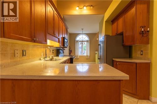 Wood cabinetry kitchen with stone-finish countertops, tile backsplash, and stainless steel appliances - 4066 Medland Drive, Burlington, ON - Indoor Photo Showing Kitchen With Double Sink
