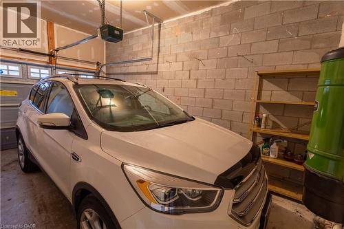 Garage with exposed cinder block walls, an automatic garage door opener, and a built-in wooden shelving unit - 4066 Medland Drive, Burlington, ON - Indoor Photo Showing Garage