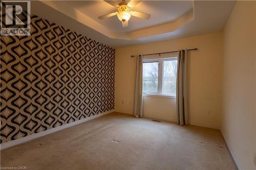 Room featuring a tray ceiling with a ceiling fan, a patterned accent wall, and a double window - 4066 Medland Drive, Burlington, ON - Indoor Photo Showing Other Room