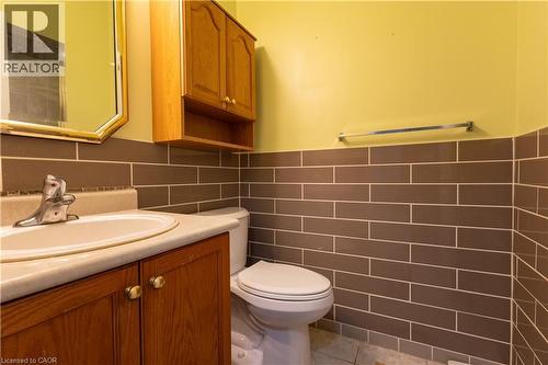 Bathroom featuring a wood-finish vanity with an integrated sink and light-toned countertop, complemented by a wall-mounted medicine cabinet with open shelving - 4066 Medland Drive, Burlington, ON - Indoor Photo Showing Bathroom